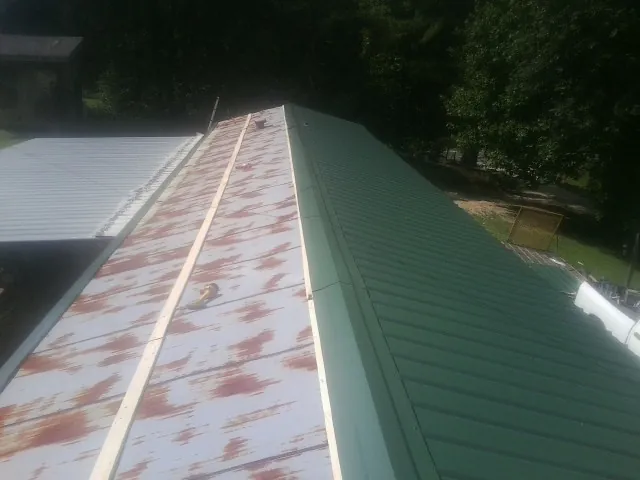 Old rusted panels beside newly installed green metal roofing — Wind Damage Roof Repair by Roofing Brothers in Cecil