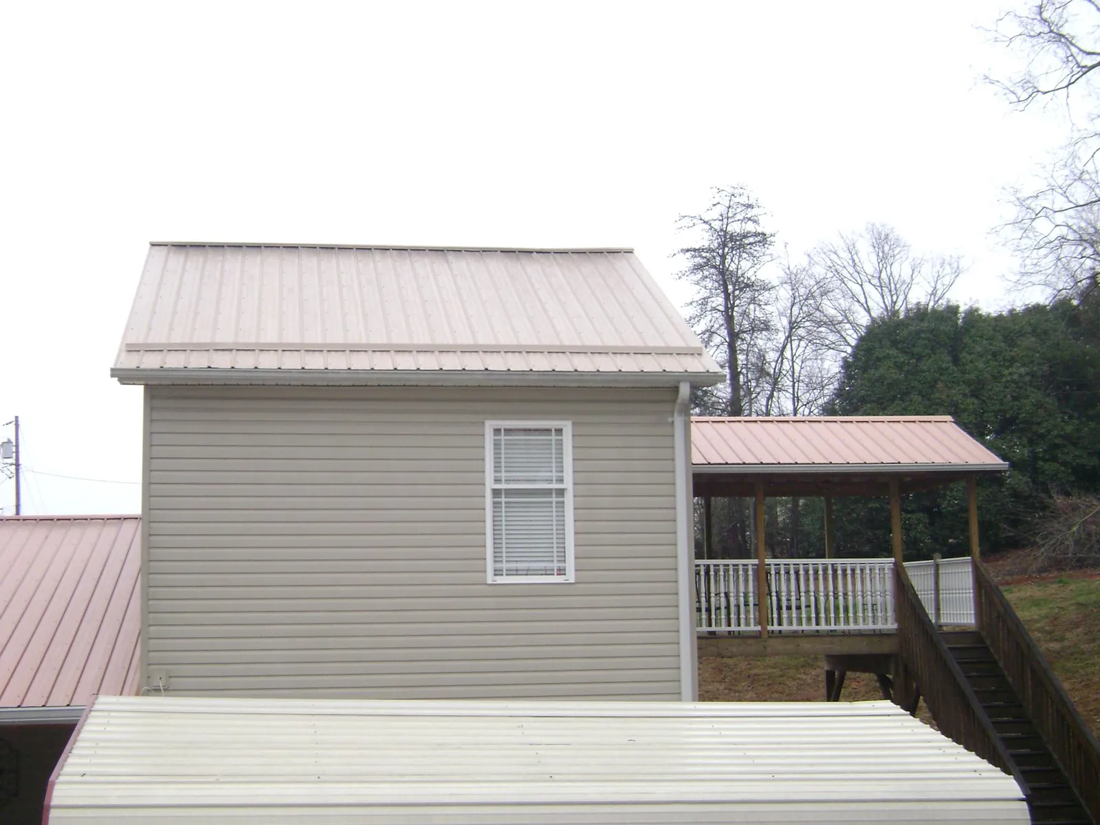 Tan metal roofs on a two story addition and attached porch, from a Roof Replacement job in Cecil